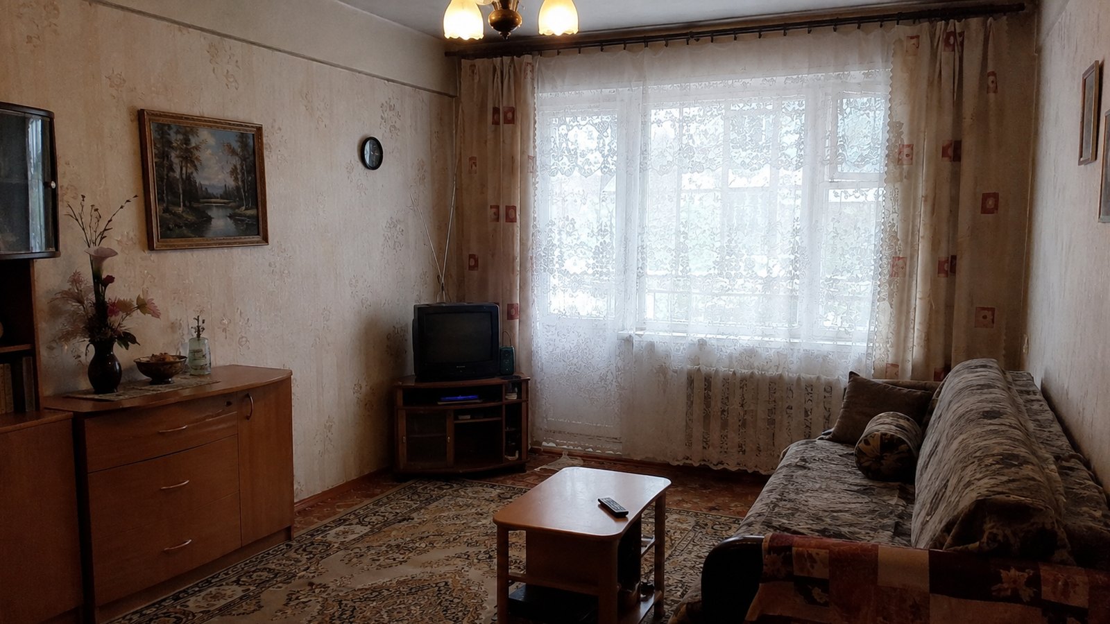 Исходное фото: комната со старой мебелью – сервант, кинескопный телевизор, ковёр на полу, обои в цветочек